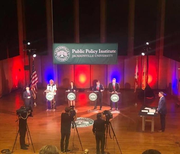 image shows politicians on stage at a debate.