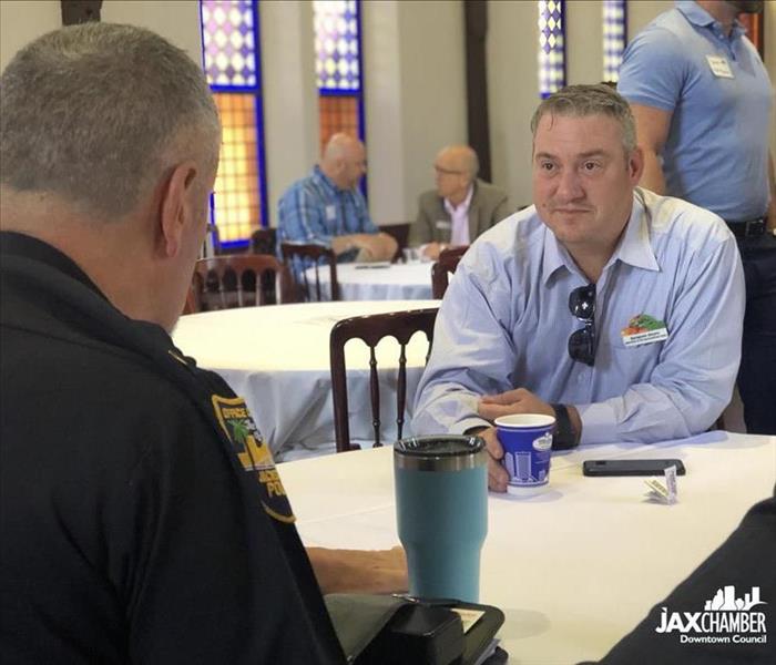 Image shows a man talking with a police officer at a breakfast event in a church.