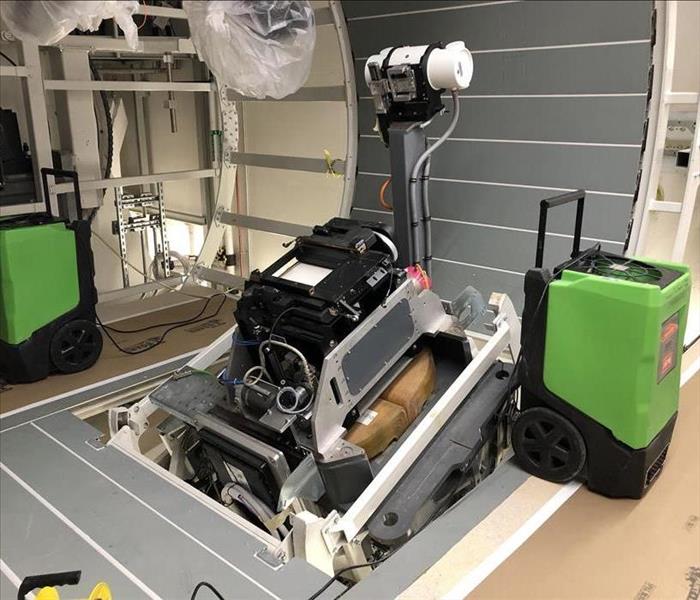 Image shows a Proton Therapy Machine between two SERVPRO green dehumidifiers.